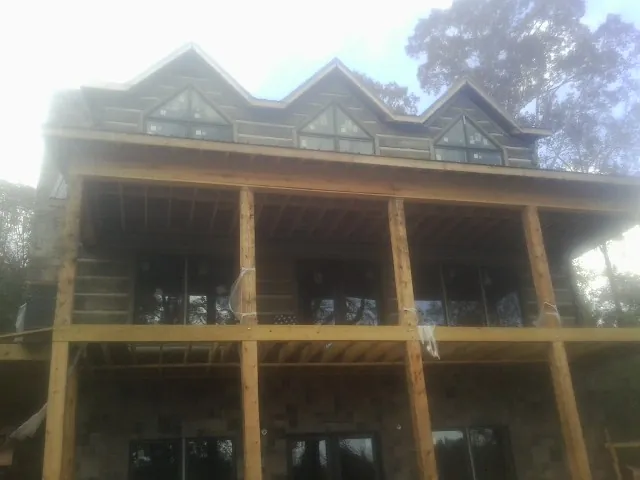 Dormers and porch framing on a large log home under construction — Roof Coating work by our crew in Sutersville
