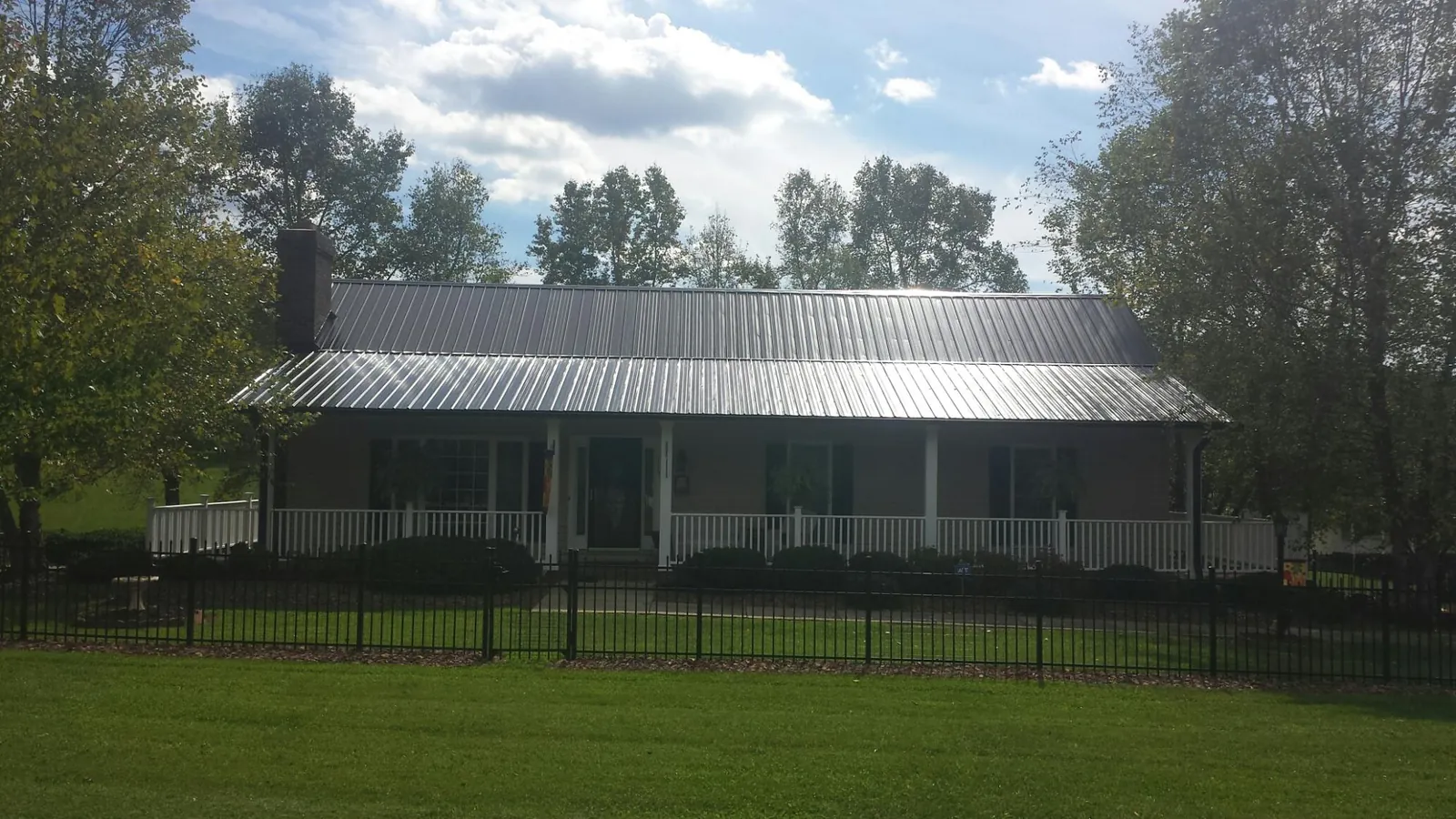 Gray metal roof on a brick ranch with a full width front porch — Gutter Guard Installation work by our crew in Sutersville