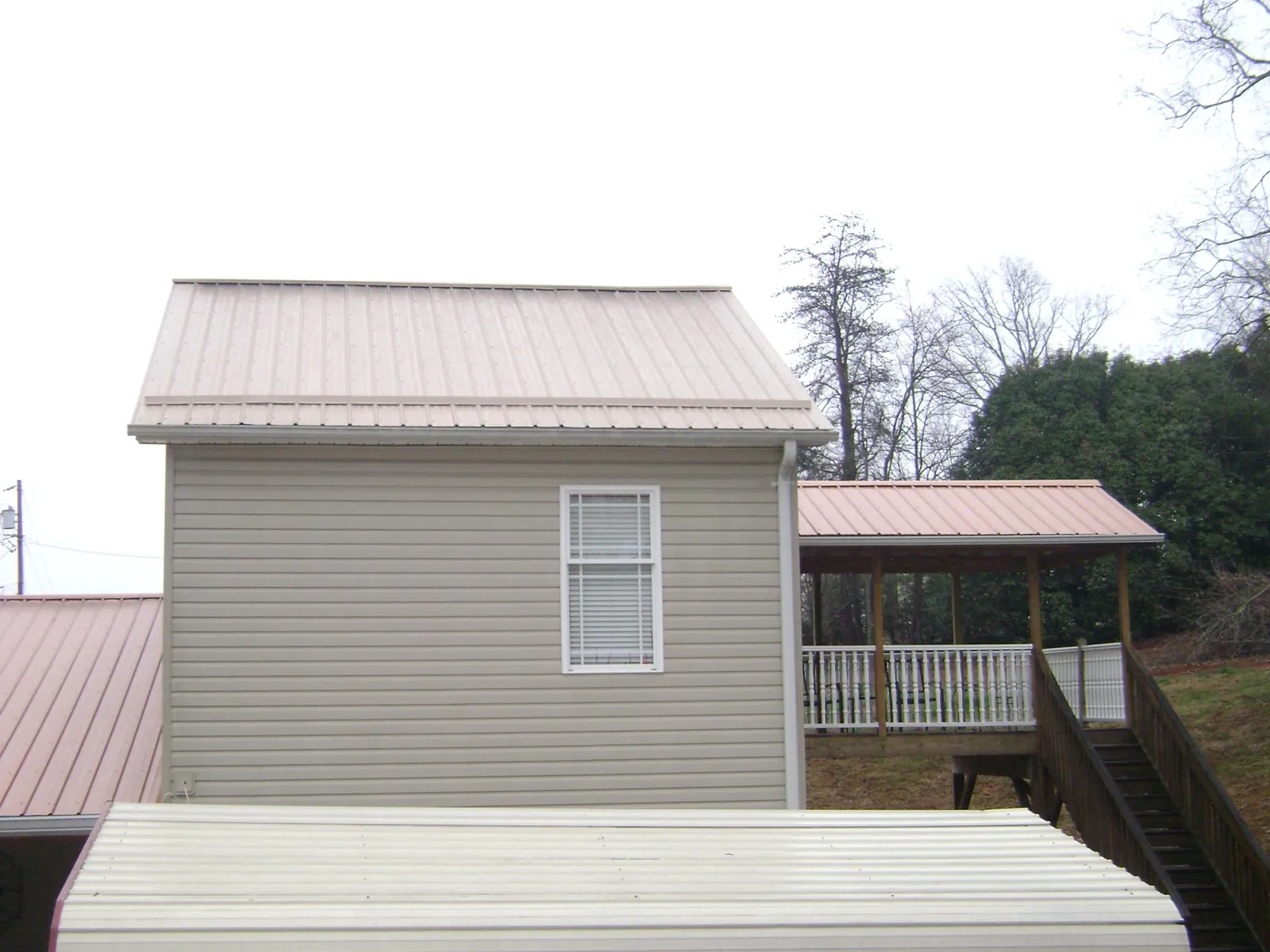 Tan metal roofs on a two story addition and attached porch, from a Roof Replacement job in Sutersville