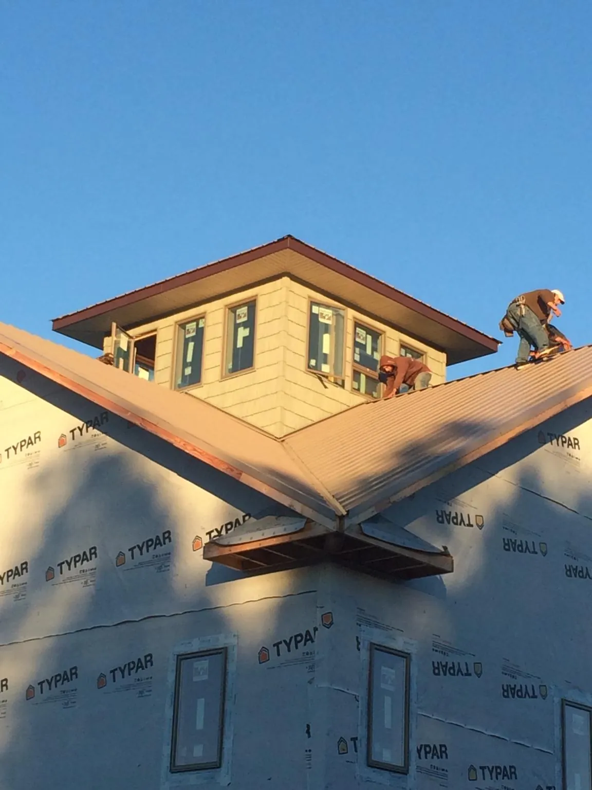 Roofers working around a rooftop cupola on a new metal roof at sunset — Roof Waterproofing in Sutersville by Roofing Brothers
